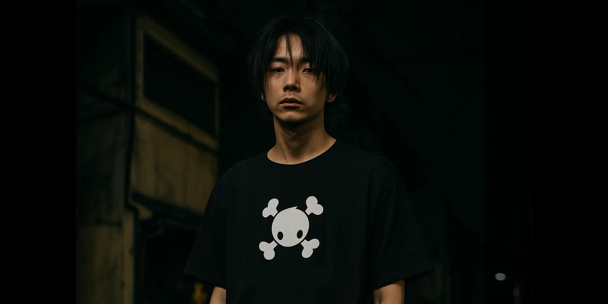 Person wearing a black t-shirt with the 'Bones' skull design in a dark setting